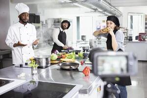 Diverse cooks team recording a fine dining cooking technique on camera, teaching beginners to learn complex meal recipes. Kitchen setup perfect for an engaging online master class. photo
