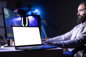 Isolated screen laptop next to man using gaming keyboard to play spaceship flying singleplayer game. Mockup notebook device and gamer navigating with spacecraft in galaxy, shooting at asteroids photo