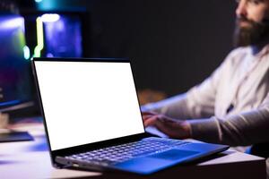Close up of mockup laptop next to man playing videogames in front of subscribers during livestream, defeating enemies. Pro gamer streaming game, wearing headphones, using isolated screen notebook photo