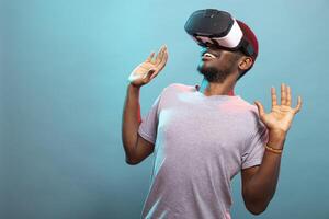 African American man using a VR headset, looking up, engaged in a futuristic 3D simulation. Young person in a casual shirt, utilizing virtual reality glasses for an immersive futuristic experience. photo