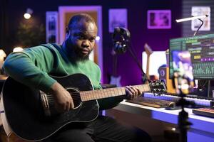 Professional composer teaching guitar lessons online on master class, recording himself playing acoustic instrument accords and explaining notes for a tutorial. Young musician making vlogs. photo