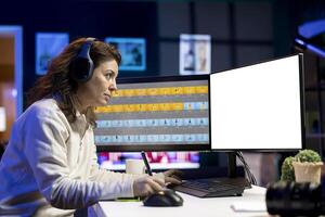 Photo editor working in independent production company using isolated screen monitor, listening music. Photographer with headphones adjusting white balance on overexposed pictures on mockup computer
