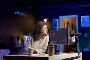 System administrator doing software debugging on PC at home, checking broken lines of code displayed on monitors. Proficient IT specialist in apartment fixing coding problems, typing on keyboard photo