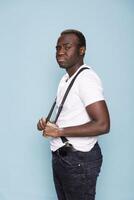 African american man adjusts his suspenders, striking a confident pose and looking directly at the camera. The clean studio setting highlights his stylish and poised presence. photo