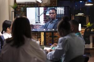 Businessman on digital monitor in virtual meeting with colleagues. Black male entrepreneur shares insights and contributes to brainstorming session on marketing strategies during videoconference call. photo