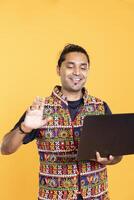 Smiling employee doing waving hand gesture, brainstorming project tasks with colleague over online videocall on laptop. Upbeat worker saluting coworker on videoconference, studio background photo
