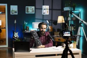 Man filming technology review of DJ controller using professional camera and microphone. Tech guru presenting sound mixer device to audience, recording with high tech equipment photo