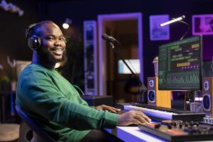 Portrait of skilled sound designer working in his home studio, adjusting volume levels on mixing console to edit old audio files. Music producer composing soundtracks on professional software. photo