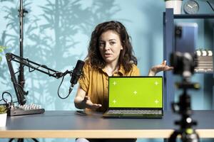 Woman doing live broadcast talking to audience about recent news headlines, reading from mockup laptop. Online show host talking with subscribers, presenting information from isolated screen notebook photo