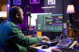 Artist playing electronic piano keyboard notes and recording audio files to use mix and master techniques, editing recordings to edit sound effects. Musician composer operating on synthesizer gear. photo
