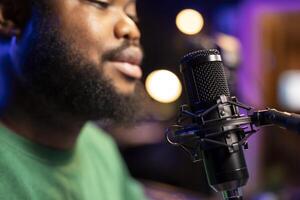 Singer performing his new track creation on a microphone, manipulates his audio files recordings with mixing and mastering techniques. Artist composer operates on stereo equipment. Close up. photo