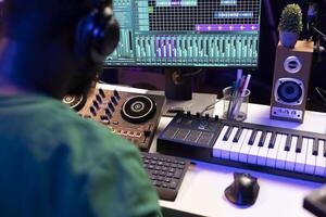 Sound engineer mixing and mastering new music on console and daw software in home studio, twisting pre amp knobs. Talented composer producing songs for the industry. Close up. photo