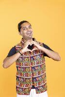 Portrait of happy nice man doing heart symbol shape gesture with hands, showing kindness. Jolly loving person showing love gesturing, being appreciative, isolated over studio backdrop photo
