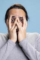 Scared terrified guy feeling extremely afraid about something in studio, showing real anxiety and concern in front of the camera. Young person being horrified and distraught, horror scenes. photo