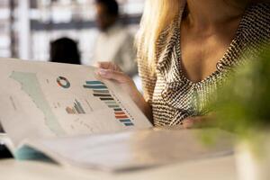 Corporate businesswoman reviewing data analytics at work, doing report writing to ensure project progress. Multinational company worker managing deadlines and financial planning. Close up. photo
