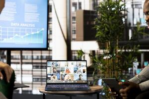 African american manager discussing with collaborators working from home, holding videoconference meeting using laptop to present new project. Man having conversation with workers in videocall photo
