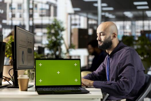 Young corporate analyst handling financial tasks next to chroma key display, preparing a project briefing for the multinational company. Manager reviewing numbers and performance metrics. photo