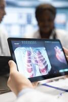 Medics and his staff meet to discuss lungs radiography for patient care strategy in a treatment center. Medical team analyze organs x rays and healthcare records to focus on diagnostics. Close up. photo