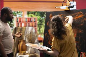 Talented artist and her apprentice engage in finger painting hobby in art and craft workshop, using a modern painting technique to create an abstract masterpiece. Vibrant colors on the canvas. photo