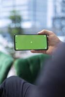Chief executive officer looks at his smartphone with isolated mockup at the office, following market trends and making data driven decisions. Entrepreneur working on a success story. photo
