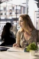 Corporate businesswoman reviewing data analytics at work, doing report writing to ensure project progress. Multinational company worker managing deadlines and financial planning. photo