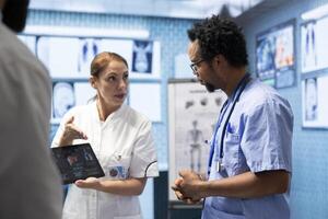 Doctors discuss x ray and ct scan results for a new treatment plan in a medical office. Team of licensed experts working to provide diagnostic and healthcare services, examine organs radiography. photo