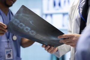 Radiologists team examine x ray scan results in a treatment center facility. Team of licensed healthcare experts working in cabinet to provide medical services for diagnostic control. Close up. photo