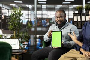 Man showing isolated screen tablet to employees, presenting them research data needed for finding business insights and finishing project task. Employees in office analyzing data on mockup device photo