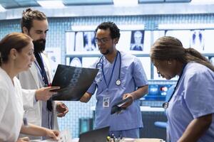 Physicians and radiologists examine x ray scan results to develop effective treatment plan. Doctors doing teamwork at a private clinic to ensure radiography based diagnostics for healthcare. photo