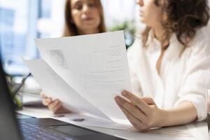 Recruiters browsing through files, hiring for newly opened company position, looking over CVs matching job description. HR staff members analyzing candidates resumes in office photo