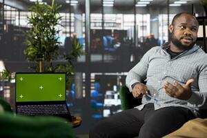 Isolated screen notebook next to manager working in office workspace, coordinating company administrative operation. Supervisor reviewing business data metrics on chroma key laptop photo