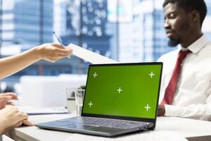 HR expert discussing with woman, vetting applicants to ensure skills match role needs using green screen laptop. Headhunter assessing candidate work experience using mockup notebook photo