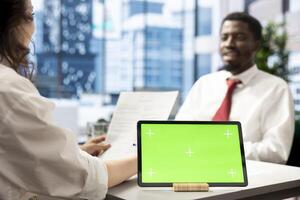 Recruiter using green screen tablet after candidate qualifications aligned with company expectations. HR employee verifying resume on chroma key device before agreeing terms with job applicant photo