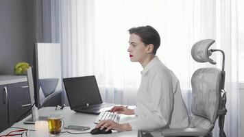 Focused female freelancer multitasking with smartphone and laptop in a bright office video