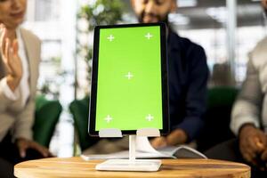 Focus on isolated screen tablet used by employees in blurry background preparing for business meeting. Close up of chroma key device used by people doing research analysis for startup organization photo