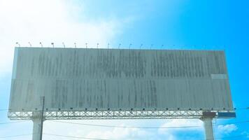Blank billboard against a bright blue sky with some clouds. Billboard is supported by metal beams and posts. Suggesting it ready for advertising. Junction of No 3 Road of Chanthaburi Thailand. photo