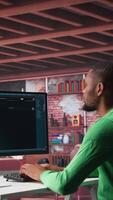 Vertical African american guy at home asks questions to AI chatbot virtual assistant, typing user prompts to generate information with the artificial intelligence tool. Machine learning. Camera B. video