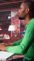 Vertical Black guy using text to image AI chat software at his modern loft. Digital screen shows generative content via neural networks, enhancing predictive models and visualized data. Camera B. video