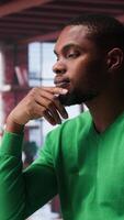 Vertical African american guy thinking about new ideas to increase clients numbers, multitasking to find a solution for financial growth. Young remote worker uses his creativity. Camera B. video
