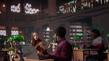 Diverse students working together on a college assignment at the library, consulting the general database and academic collection of specialty books. Young people focus on high grades. Camera B. video