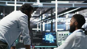 Server hub manager checking data analytics graphs, congratulating worker. Data center team leader doing fist bump with admin using artificial intelligence showing system metrics, camera B video