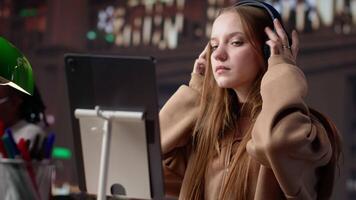 Young girl listening to educational documentary on laptop and taking notes, using modern non conventional way to study in the quietness of university library. Collects academic data. Camera A. video
