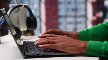 Freelancer creating articles content for his online blog at home desk, writing and working on storytelling with his laptop. Black guy composes social media posts, multitasking. Camera A. video