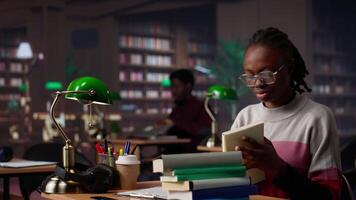 African american girl does bachelor paper research for citations and other information, using the database at the campus library. Intelligent student working on her diploma. Camera A. video