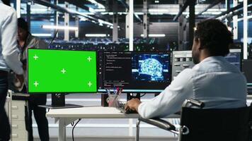 Data center worker with paraplegia using green screen PC to apply node tree programming. Server hub admin with disability uses visual programming on mockup computer to identify data patterns, camera B video