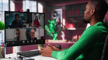 Remote worker looking at PC monitor discussing with coworkers during videocall from home. Computer display used by teleworker in remote teleconference meeting with colleagues. Camera A. video