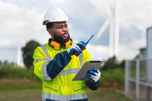 man in a yellow safety vest is pointing at a tablet while wearing a hard hat photo