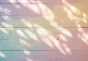 Pastel painted wood surface with colorful speckles and soft sunlight shadows on textured planks captured in abstract artistic background closeup photo