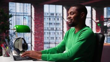 African american remote worker at home doing online research, writing down and gathering important data. Teleworker focused on reading articles, daily assignments at home. Camera A. video