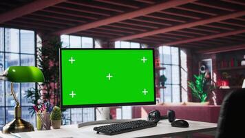 Modern home office featuring elegant desk with green screen display. Surrounded by minimalist furniture and neutral tones, upscale loft blends tranquility with chic professional design. video